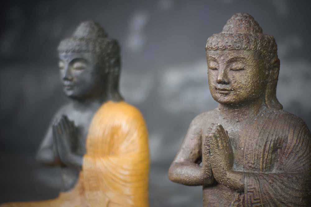 Zittende Buddha met handen in gebed