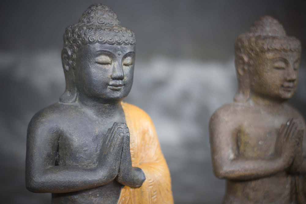 Zittende Buddha met handen in gebed